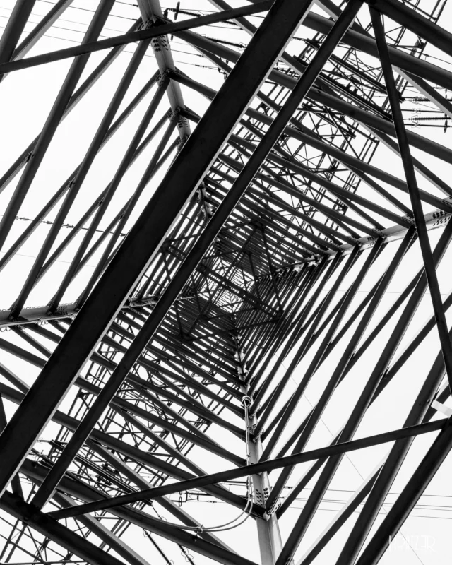 Verwirrte Komplexität –  Ein wirres Geflecht aus Linien und Streben treibt die Vertikale ins Extreme. Eine Struktur, die den Raum nicht nur ordnet, sondern auch erobert. Diese Komplexität ist notwendig, um die moderne Welt zu versorgen. Sie droht aber auch, die Einfachheit zu ersticken.

Sind wir bereits Gefangene der Jagd nach Expansion und Leistung? Wo verweilt der Minimalismus? Welchen Preis zahlen wir am Ende für diese Komplexität, die wir in unser Leben einziehen lassen?

#VerwirrteKomplexität #Aggressiv #Geometrie #Strommast #Komplexität #Einfachheit #SchwarzWeissArchitektur #Künstlerisch #Fotografie #Kunst #Kratz3r #Art #bw #blackandwhite